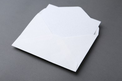 Photo of Blank greeting card in paper envelope on dark grey background, closeup