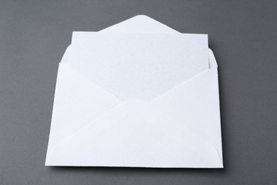 Photo of Blank greeting card in paper envelope on dark grey background, closeup