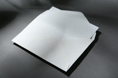 Photo of Blank greeting card in paper envelope on dark grey background, closeup