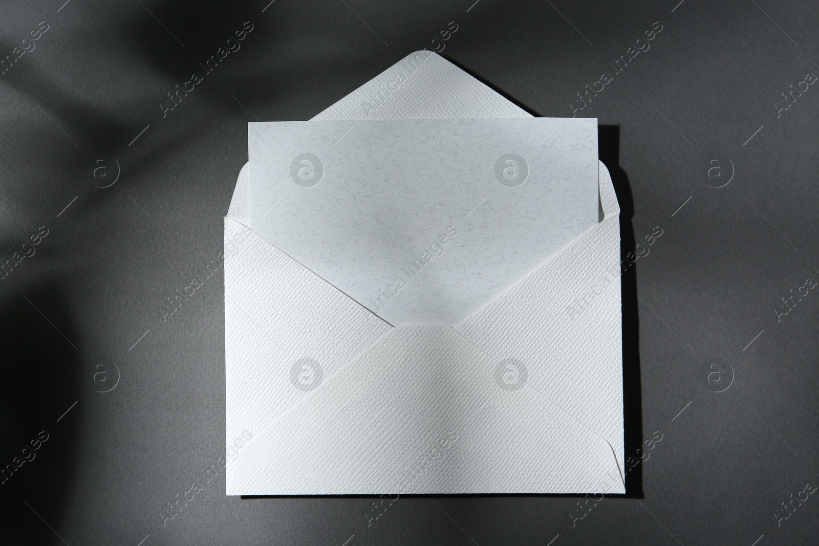 Photo of Blank greeting card in paper envelope on dark grey background, top view
