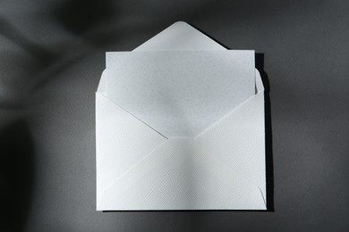 Photo of Blank greeting card in paper envelope on dark grey background, top view