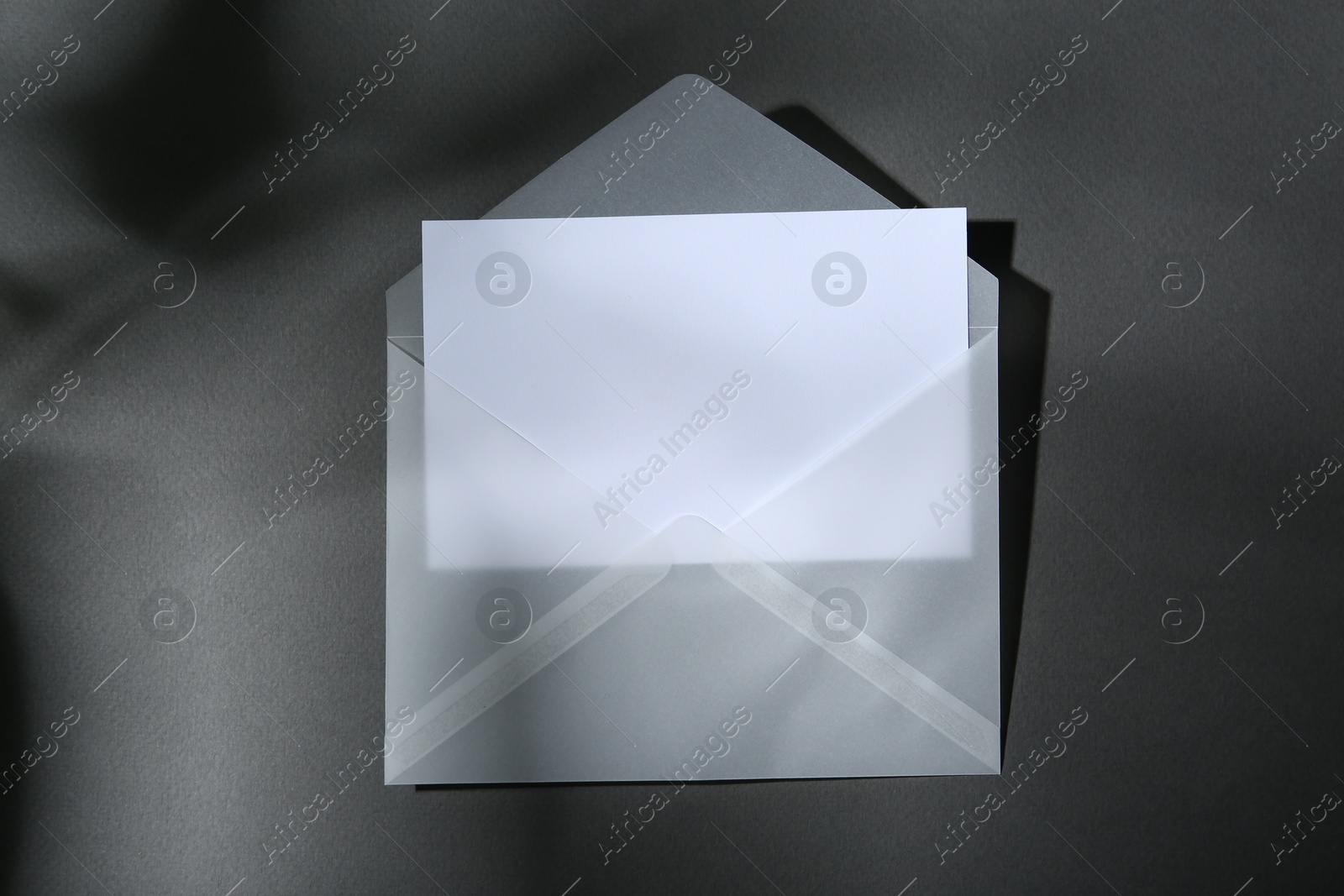 Photo of Blank greeting card in paper envelope on dark grey background, top view