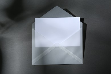 Photo of Blank greeting card in paper envelope on dark grey background, top view