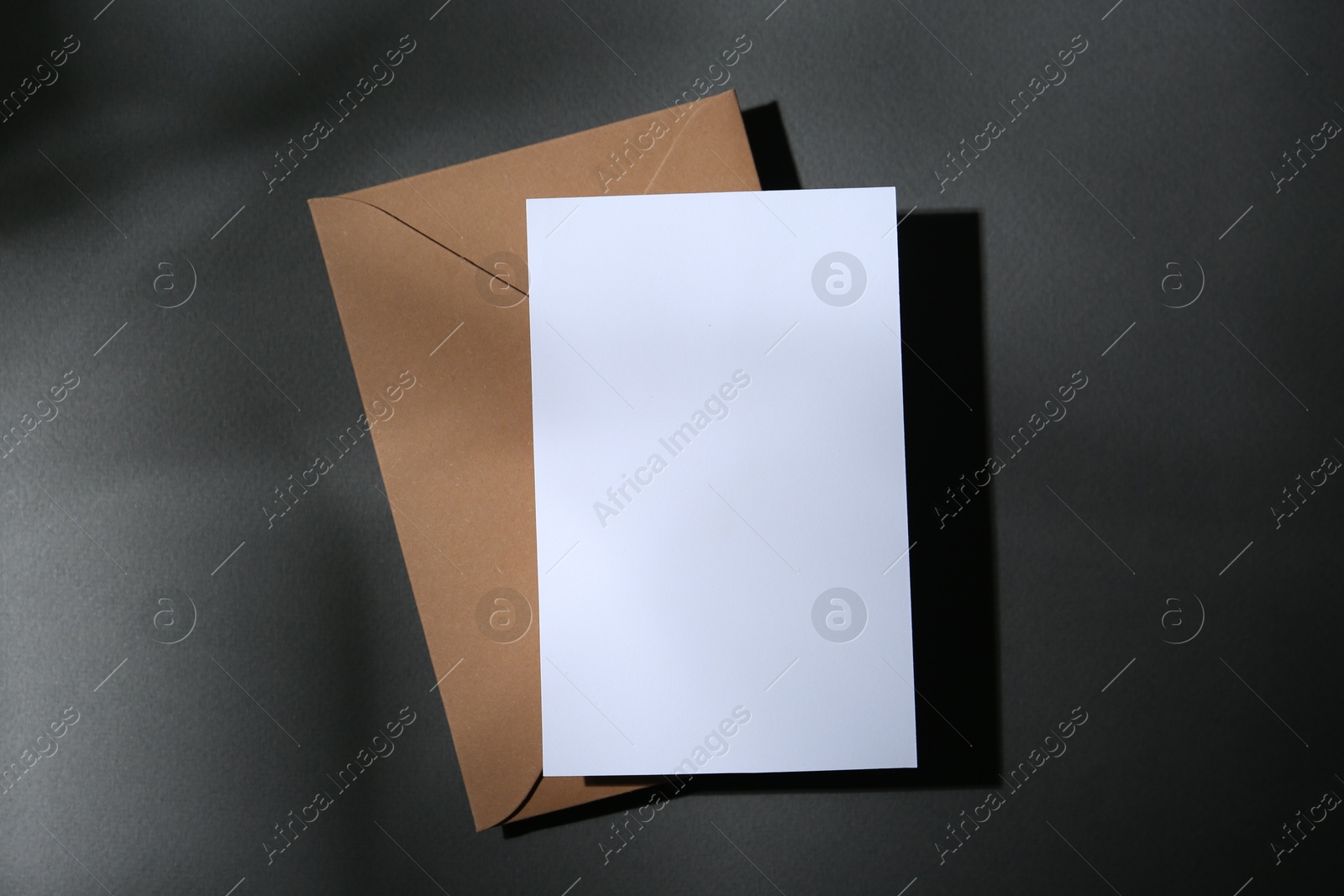Photo of Blank greeting card and paper envelope on dark grey background, top view