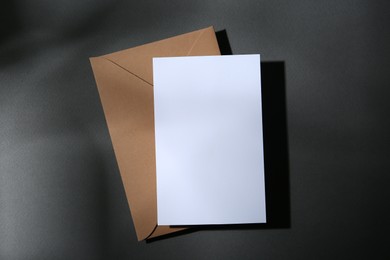 Photo of Blank greeting card and paper envelope on dark grey background, top view