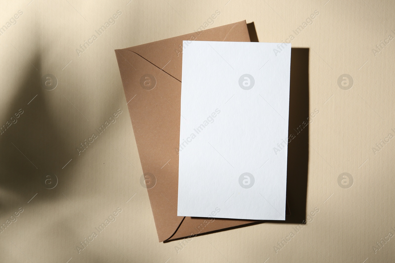 Photo of Blank greeting card and paper envelope on beige background, top view