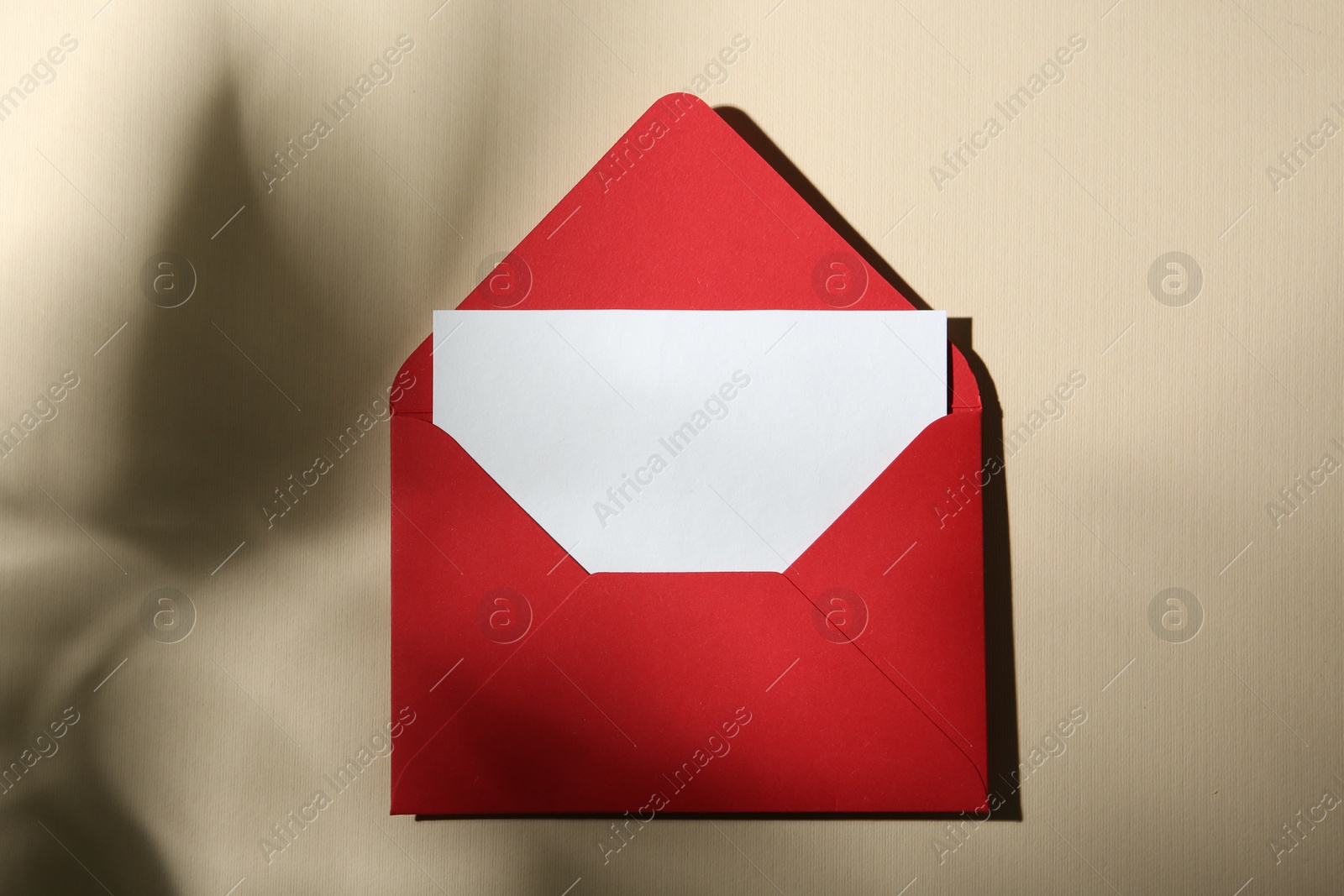 Photo of Blank greeting card and paper envelope on beige background, top view