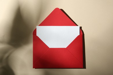 Photo of Blank greeting card and paper envelope on beige background, top view