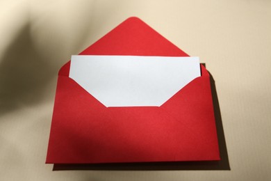 Photo of Blank greeting card and paper envelope on beige background, closeup
