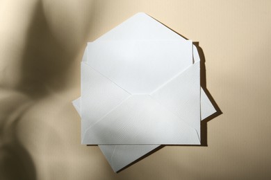 Photo of Blank greeting card and paper envelopes on beige background, top view