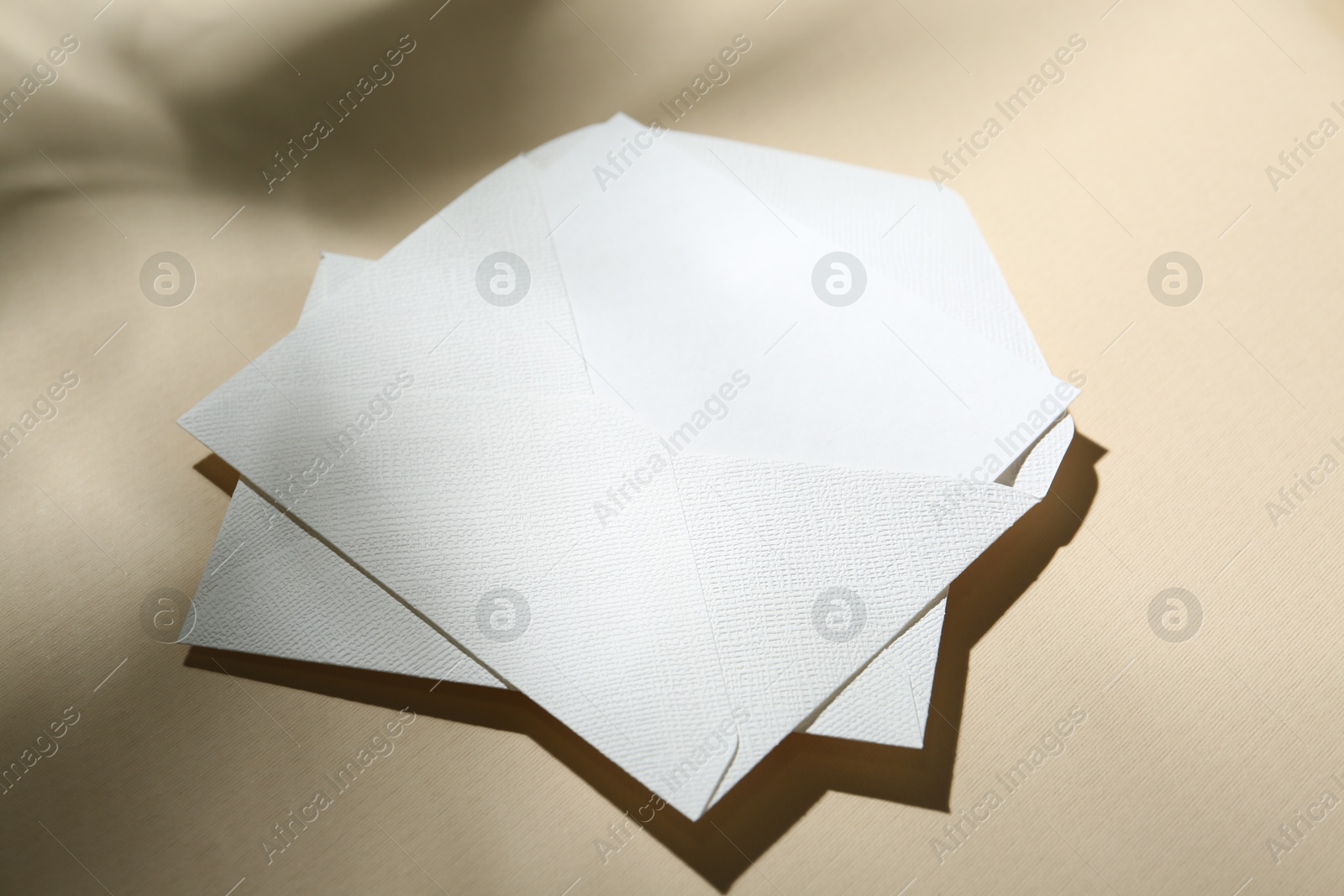 Photo of Blank greeting card and paper envelopes on beige background, closeup