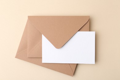 Photo of Blank greeting card and envelopes on beige background, top view