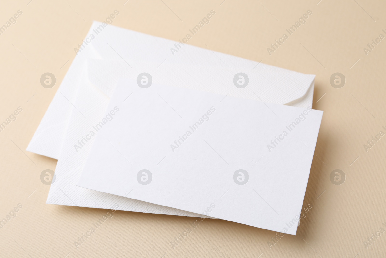 Photo of Blank greeting card and envelopes on beige background, closeup