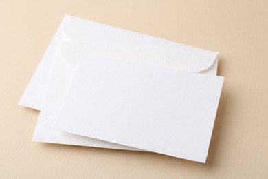 Photo of Blank greeting card and envelopes on beige background, closeup