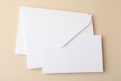 Photo of Blank greeting card and envelopes on beige background, top view