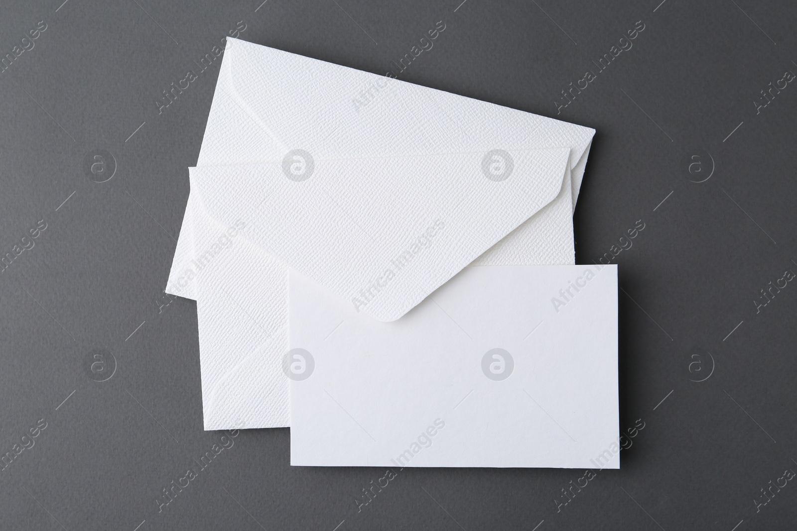 Photo of Blank greeting card and envelopes on grey background, top view