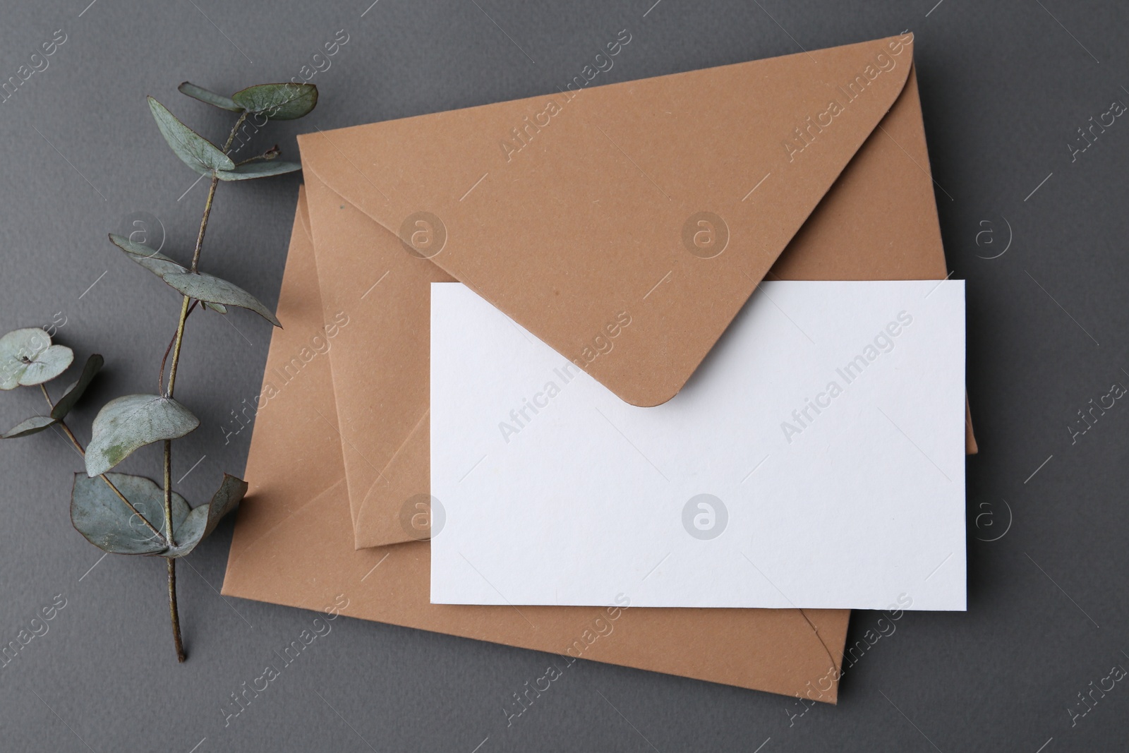 Blank greeting card, envelopes and eucalyptus leaves on grey background, flat lay Photo of Blank greeting card, envelopes and eucalyptus leaves on grey background, flat lay