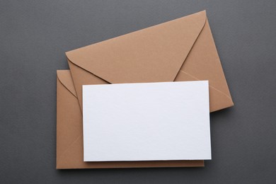 Photo of Blank greeting card and envelopes on grey background, top view