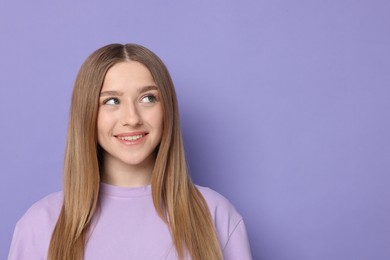 Photo of Portrait of smiling teenage girl on violet background. Space for text