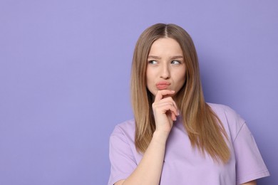 Photo of Portrait of thoughtful teenage girl on violet background. Space for text