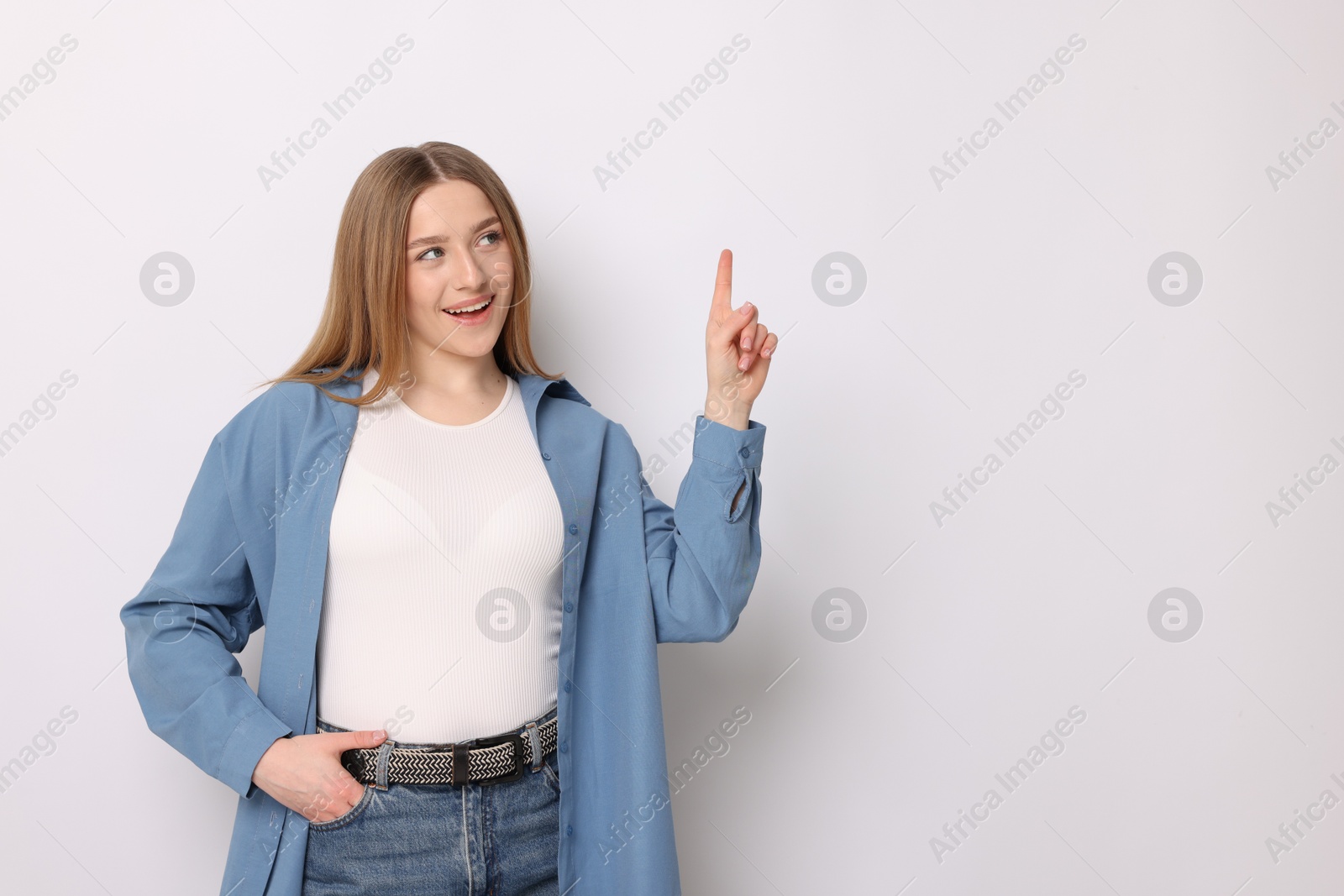 Portrait of smiling teenage girl pointing upwards on white background. Space for text Photo of Portrait of smiling teenage girl pointing upwards on white background. Space for text