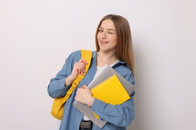 Photo of Smiling teenage girl with books and backpack on white background