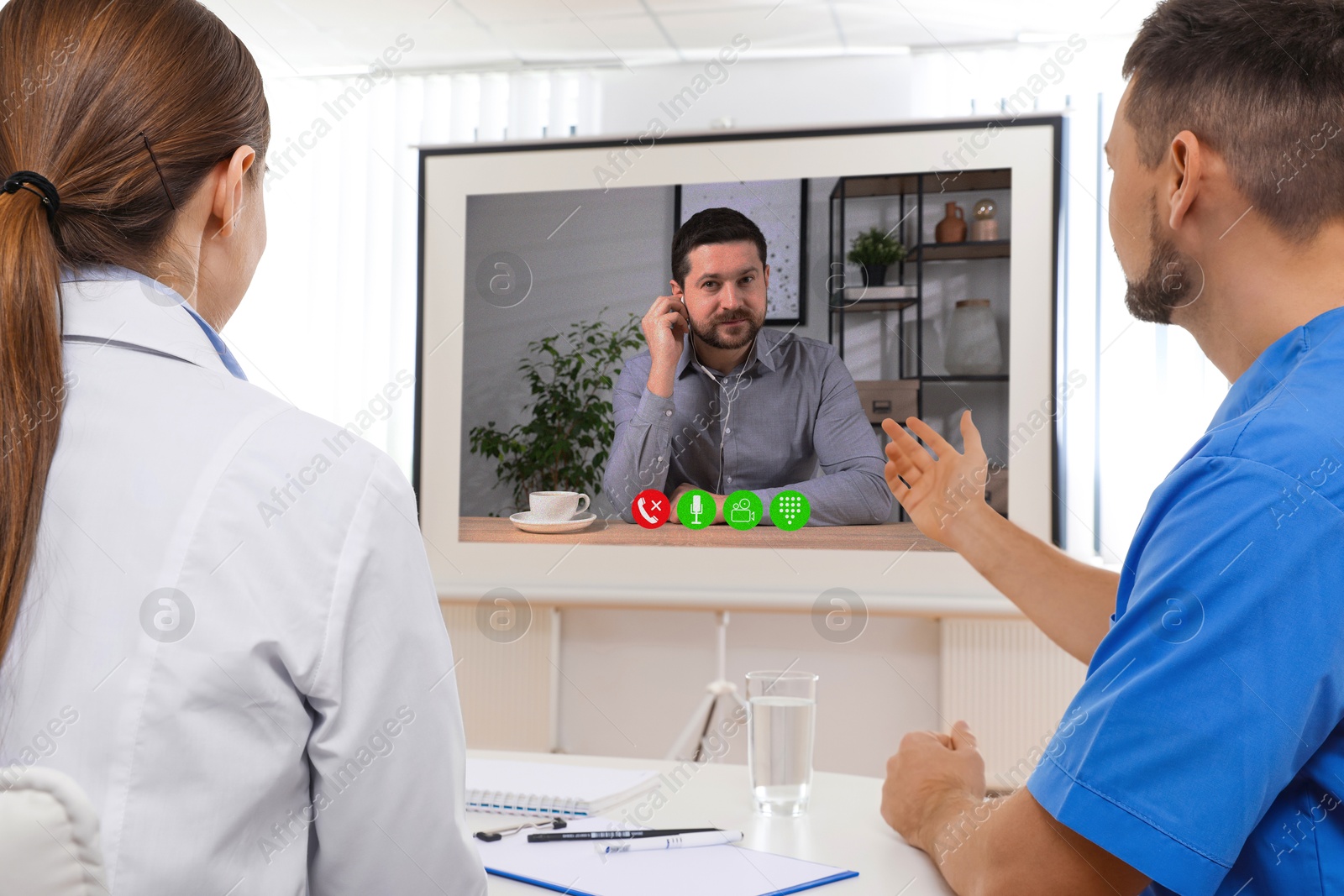 Speaker participating in lecture via online video chat. Medical workers in conference room with projection screen Image of Speaker participating in lecture via online video chat. Medical workers in conference room with projection screen