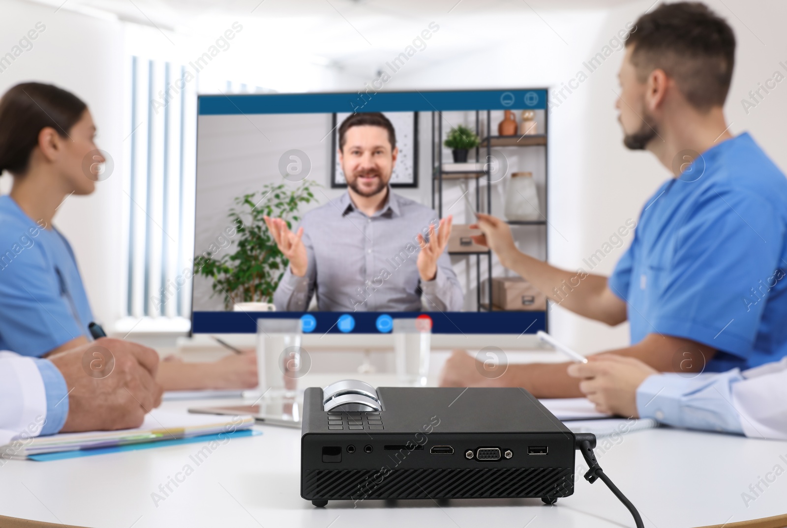 Speaker participating in lecture via online video chat. Medical workers in conference room with projection screen Image of Speaker participating in lecture via online video chat. Medical workers in conference room with projection screen