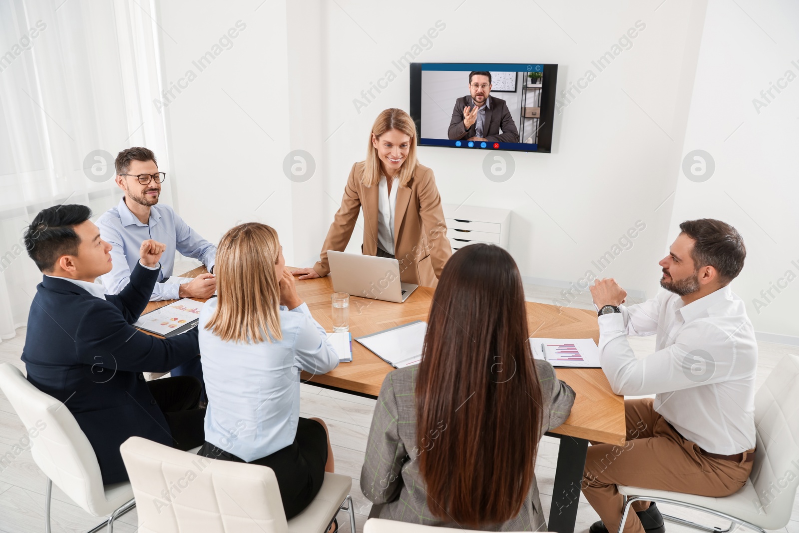Speaker participating in lecture via online video chat. Audience and coach in conference room with TV set Image of Speaker participating in lecture via online video chat. Audience and coach in conference room with TV set