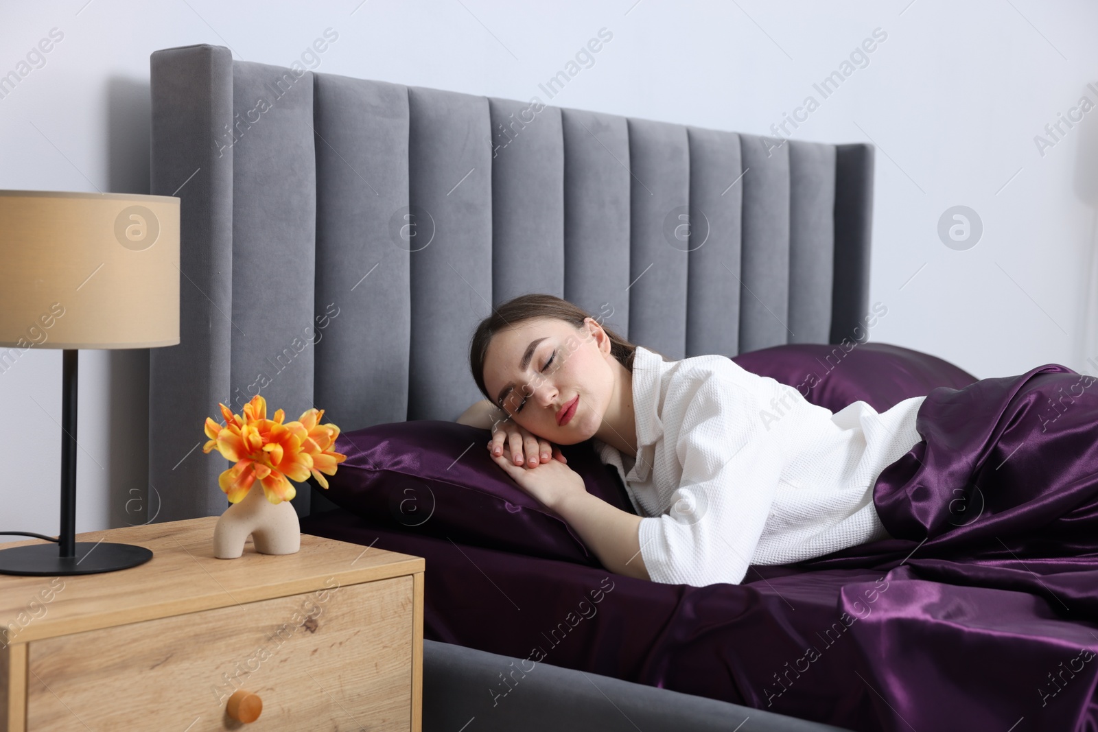 Woman sleeping in bed with purple silk linens indoors Photo of Woman sleeping in bed with purple silk linens indoors