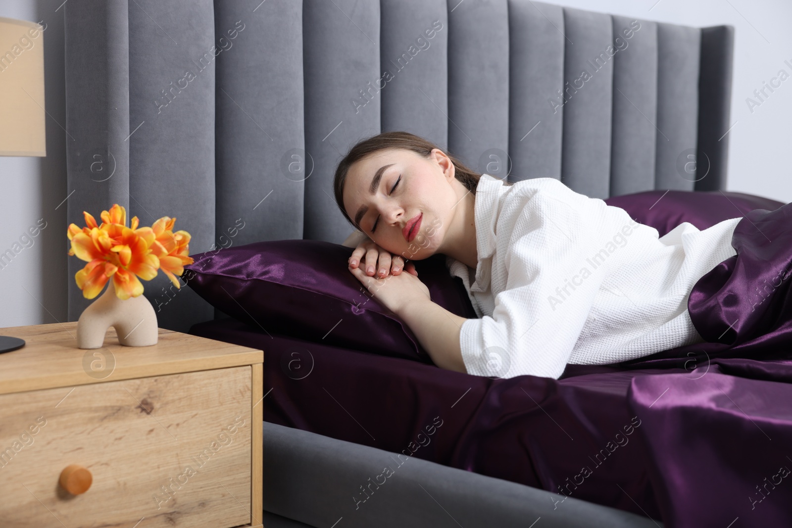 Woman sleeping in bed with purple silk linens indoors Photo of Woman sleeping in bed with purple silk linens indoors