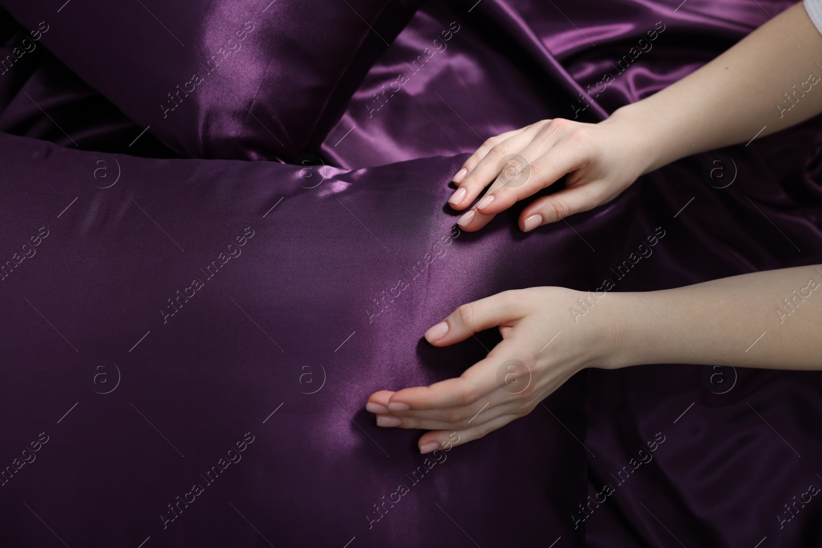 Woman with pillow on silk bed linens, top view Photo of Woman with pillow on silk bed linens, top view