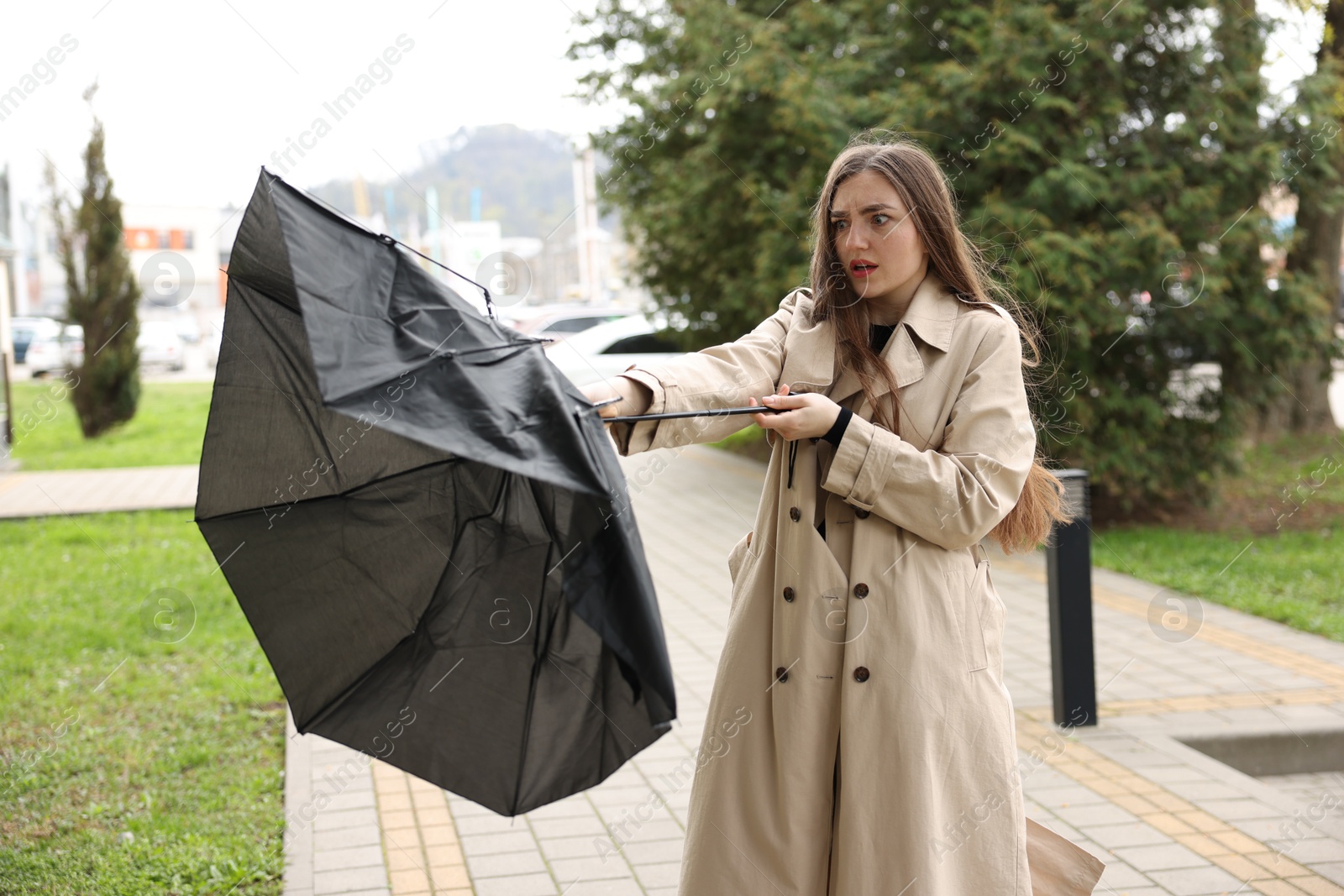 Woman with broken umbrella fighting wind outdoors Photo of Woman with broken umbrella fighting wind outdoors