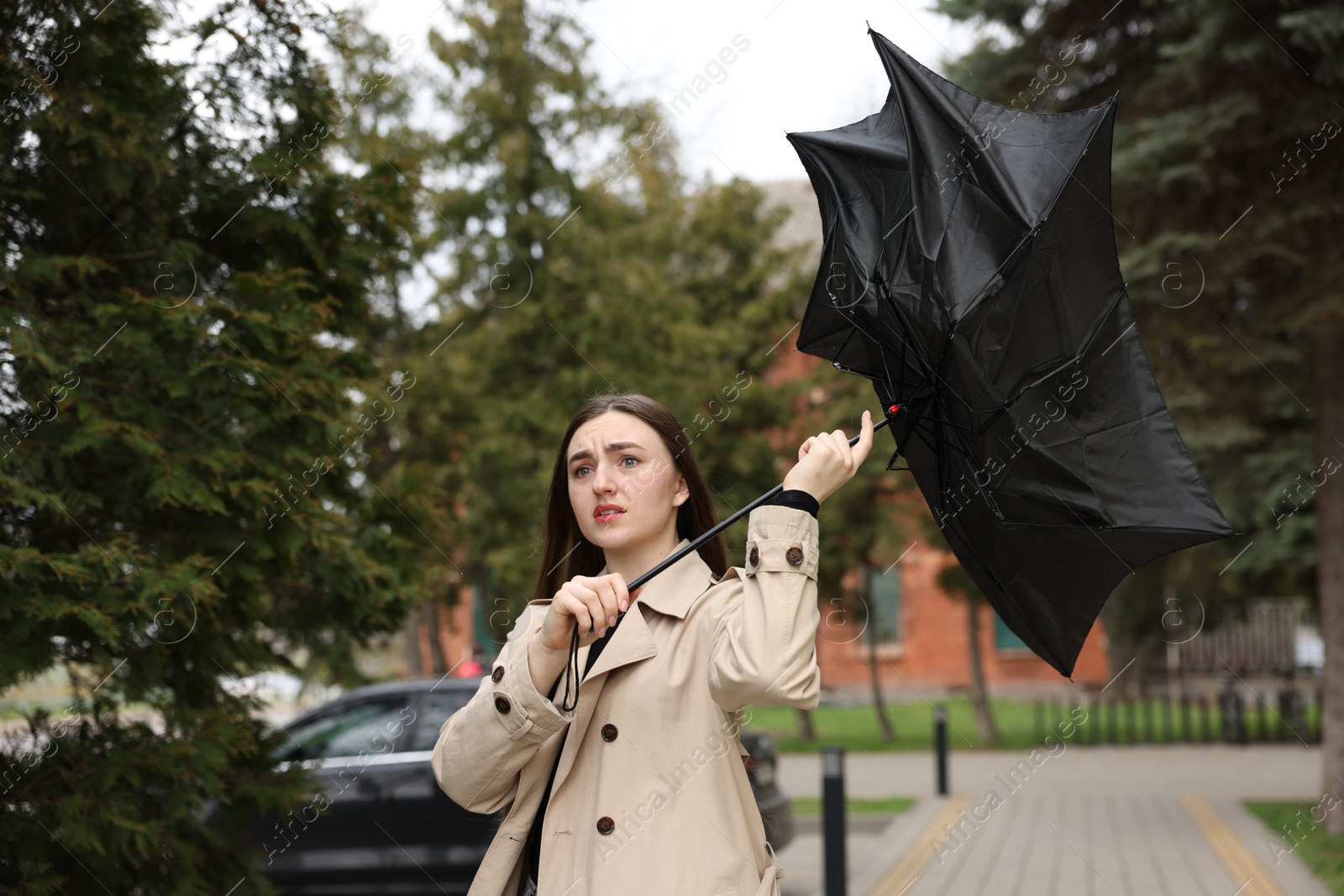 Woman with broken umbrella fighting wind outdoors Photo of Woman with broken umbrella fighting wind outdoors