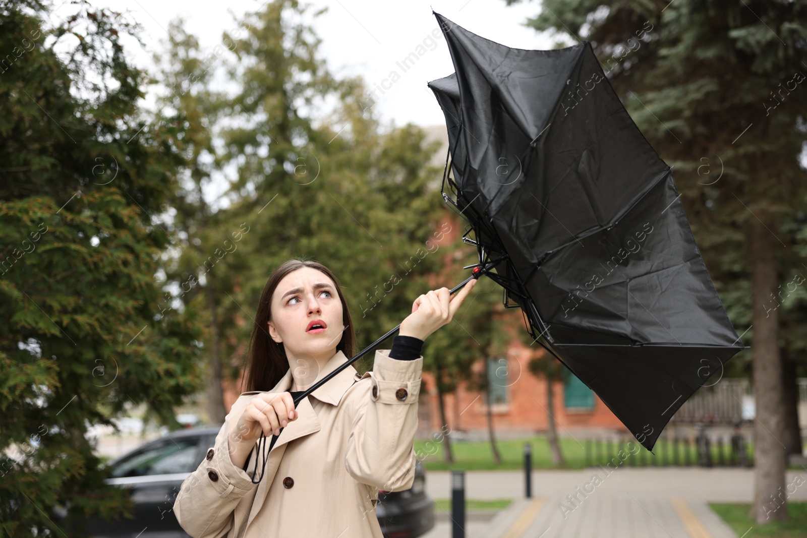 Woman with broken umbrella fighting wind outdoors Photo of Woman with broken umbrella fighting wind outdoors