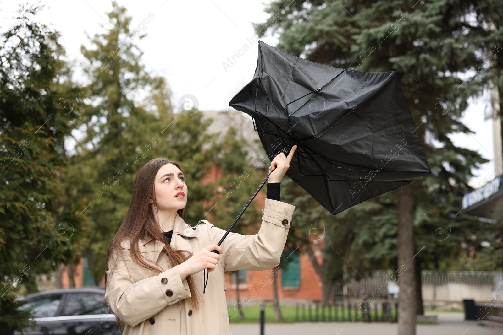 Woman with broken umbrella fighting wind outdoors Photo of Woman with broken umbrella fighting wind outdoors