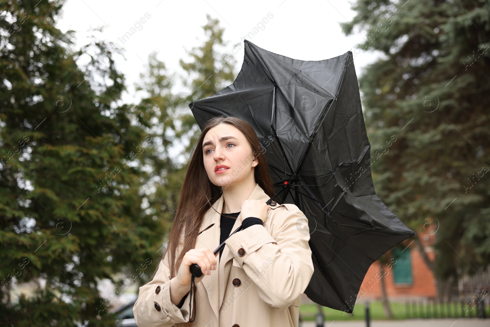 Woman with broken umbrella fighting wind outdoors Photo of Woman with broken umbrella fighting wind outdoors