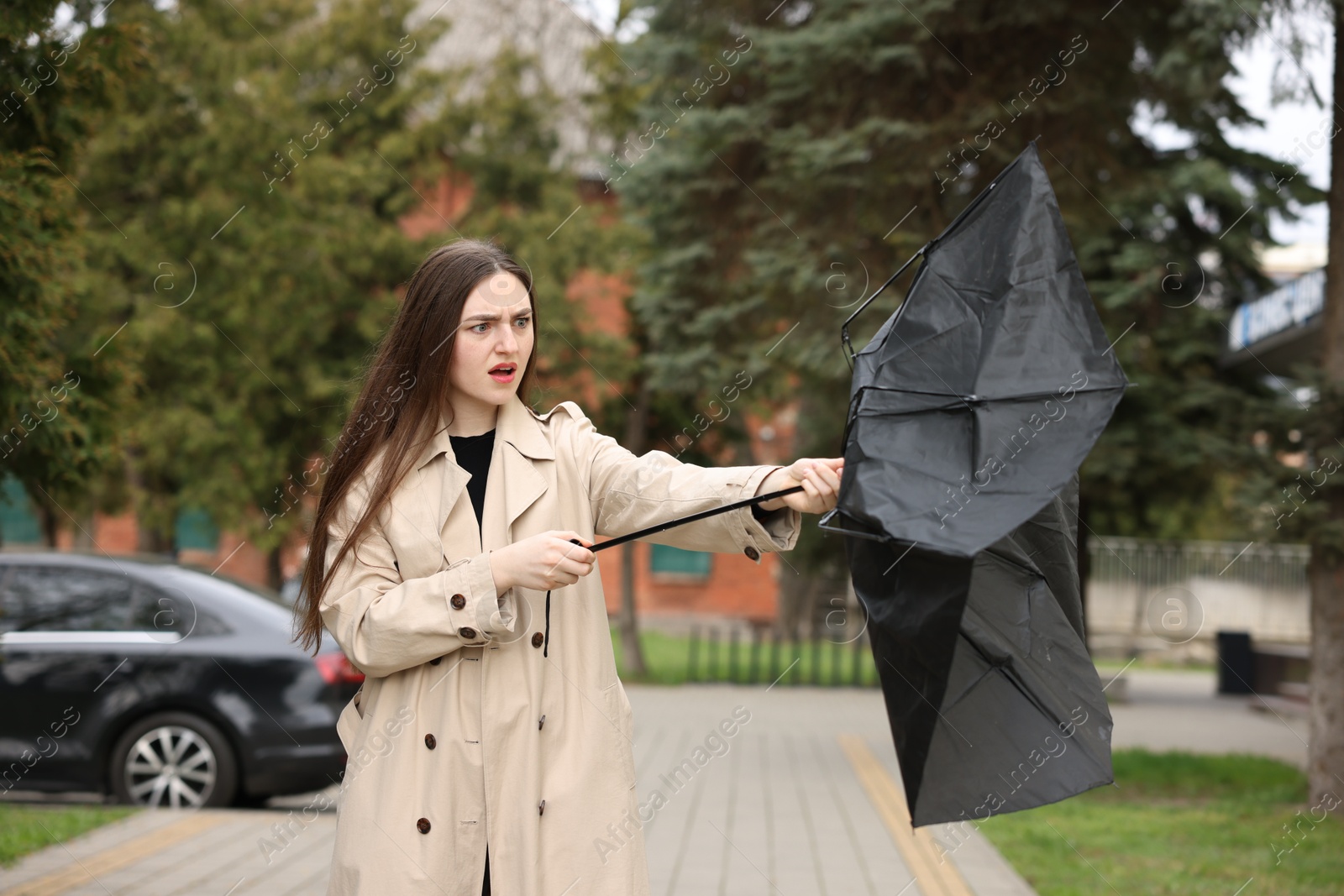 Woman with broken umbrella fighting wind outdoors Photo of Woman with broken umbrella fighting wind outdoors