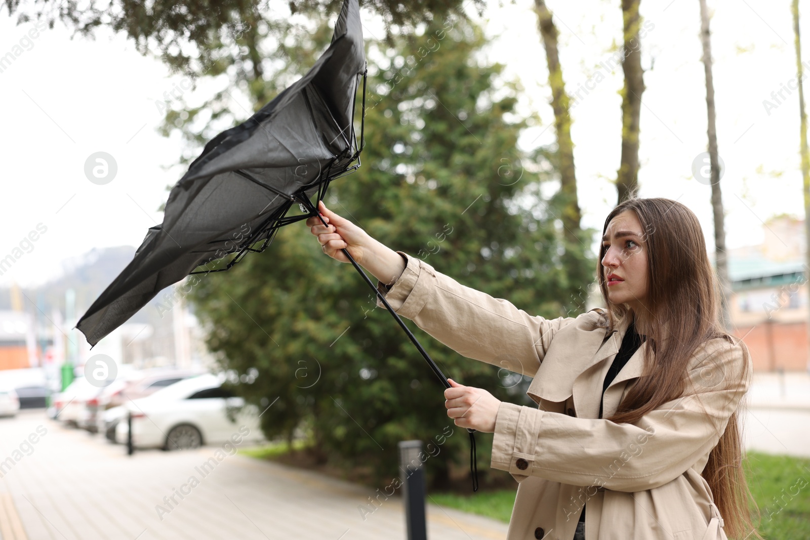 Woman with broken umbrella fighting wind outdoors Photo of Woman with broken umbrella fighting wind outdoors