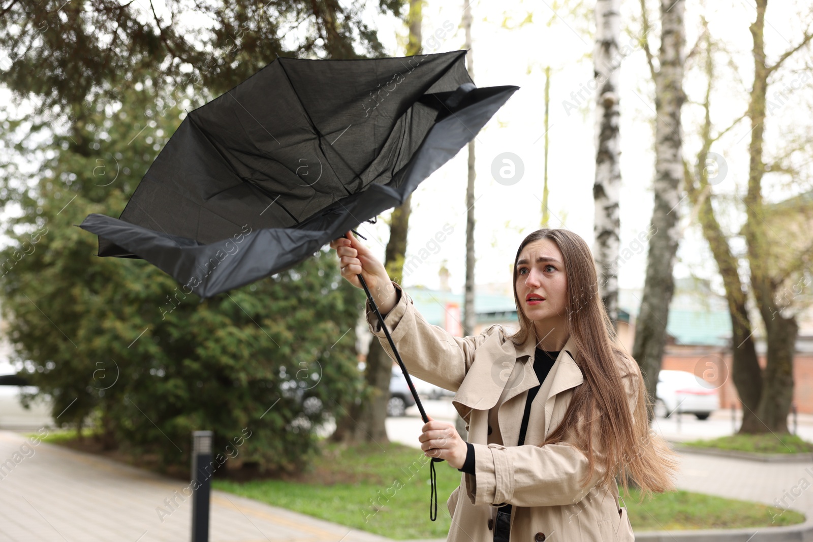 Woman with broken umbrella fighting wind outdoors Photo of Woman with broken umbrella fighting wind outdoors
