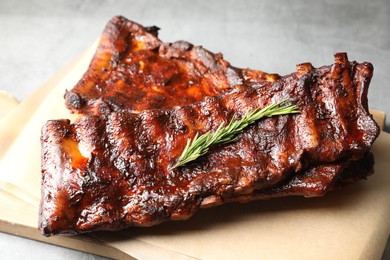 Photo of Tasty roasted pork ribs served with rosemary on light grey table, closeup