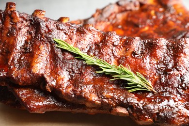 Photo of Tasty roasted pork ribs served with rosemary on table, closeup