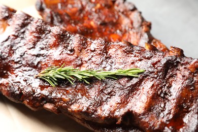 Photo of Tasty roasted pork ribs served with rosemary on table, closeup