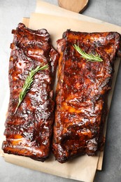 Photo of Tasty roasted pork ribs served with rosemary on light grey table, top view
