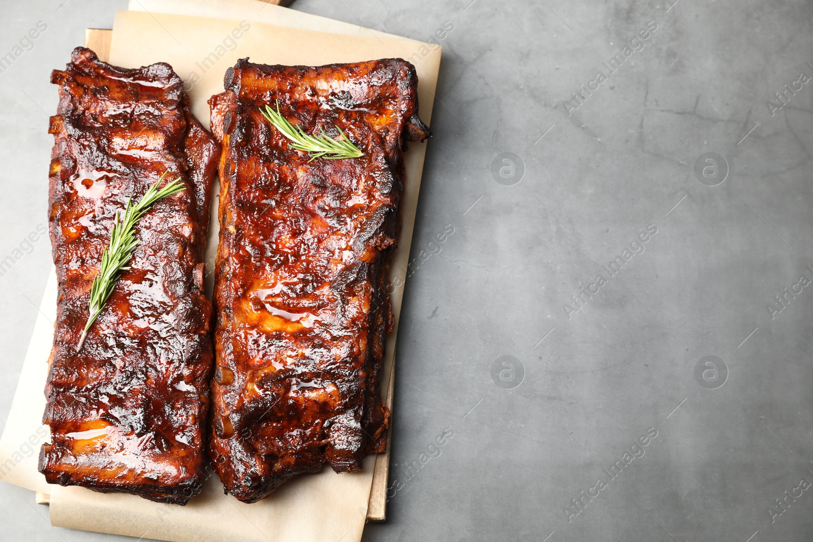 Tasty roasted pork ribs served with rosemary on light grey table, top view. Space for text Photo of Tasty roasted pork ribs served with rosemary on light grey table, top view. Space for text