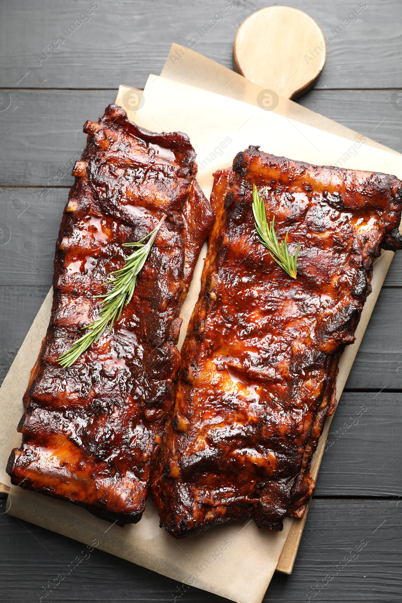 Tasty roasted pork ribs served with rosemary on black wooden table, top view Photo of Tasty roasted pork ribs served with rosemary on black wooden table, top view