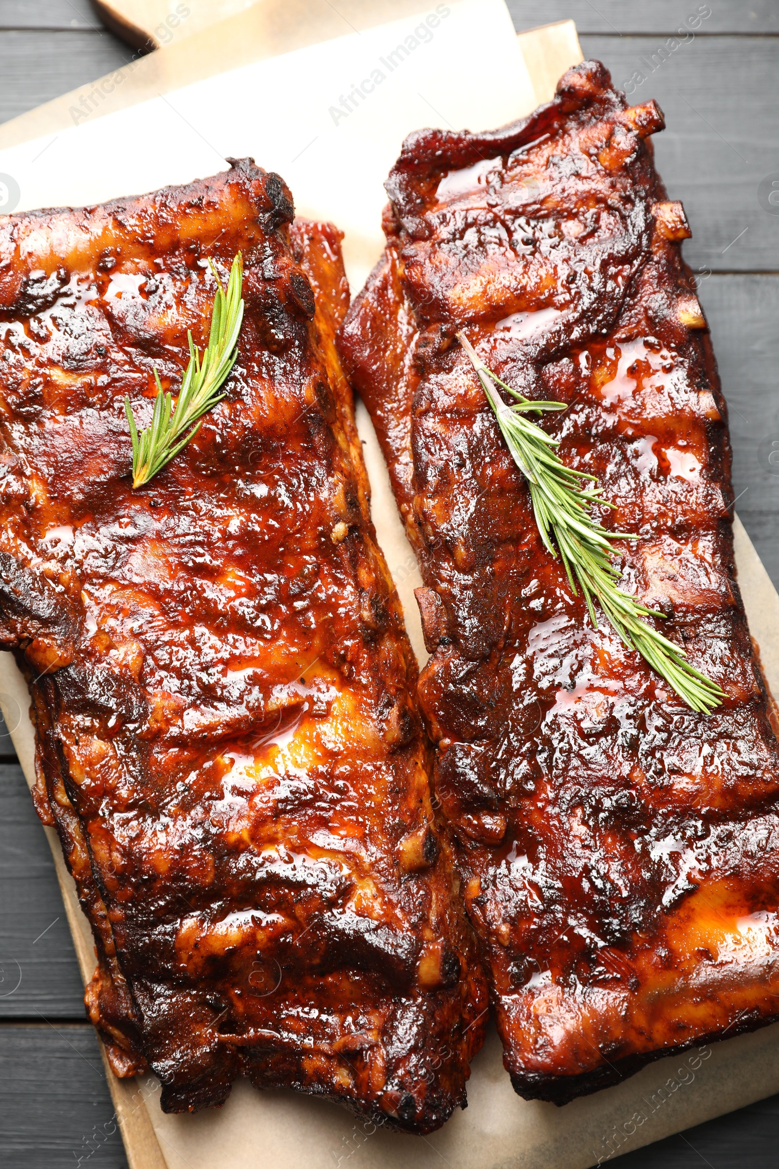 Tasty roasted pork ribs served with rosemary on black wooden table, top view Photo of Tasty roasted pork ribs served with rosemary on black wooden table, top view