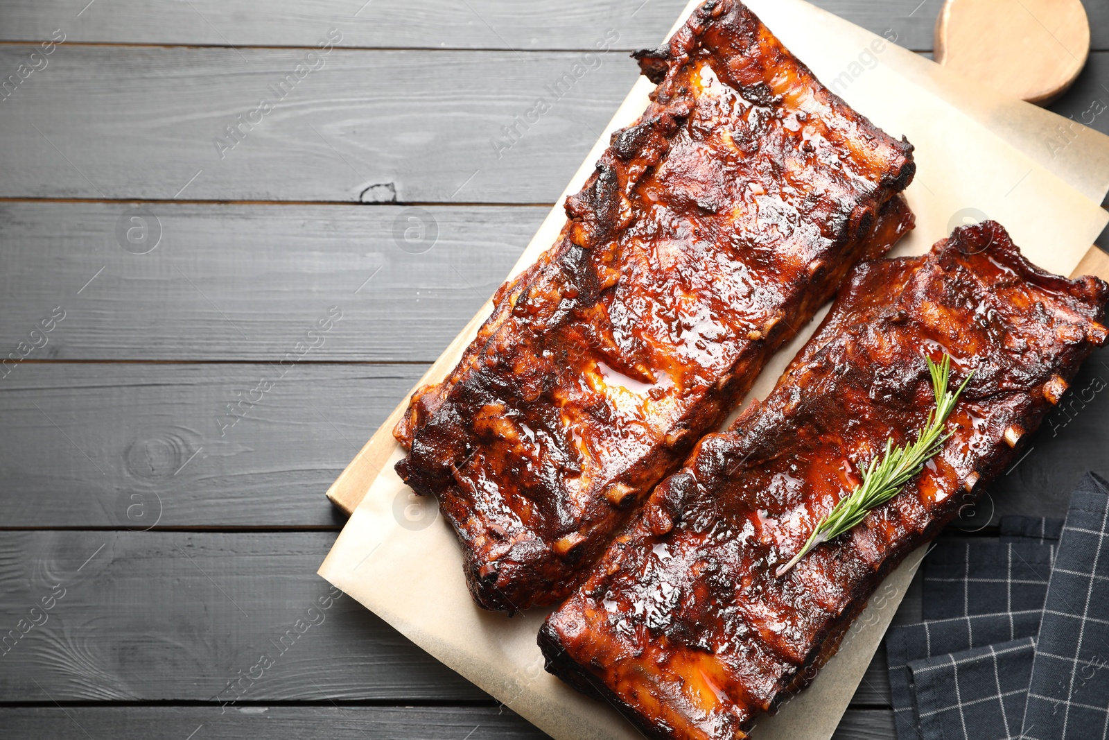 Tasty roasted pork ribs served with rosemary on black wooden table, top view. Space for text Photo of Tasty roasted pork ribs served with rosemary on black wooden table, top view. Space for text