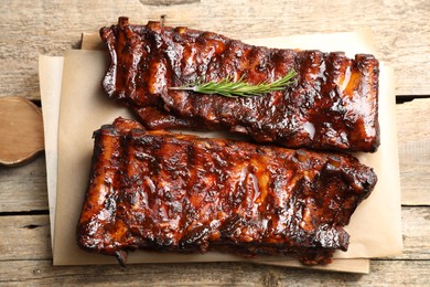 Photo of Tasty roasted pork ribs served with rosemary on wooden table, top view