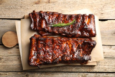 Photo of Tasty roasted pork ribs served with rosemary on wooden table, top view